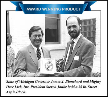 State of Michigan Governor James J. Blanchard and Mighty Deer Lick, Inc. President Steven Janke hold a 25 lb. sweet apple block.